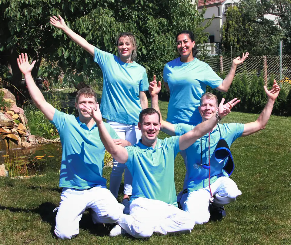 Das Team von Pflege Dorn jubelt mit erhobenen Armen im Garten